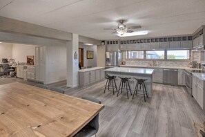 A modern kitchen with a large island, bar stools, and a dining area with a wooden table.