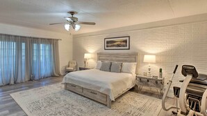 Une chambre à coucher avec un lit, un tapis de course et une grande fenêtre avec des rideaux.