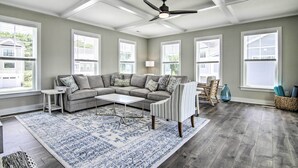 A spacious living room with a sectional sofa, a coffee table, a striped armchair, and a ceiling fan.