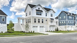 A row of modern, two-story townhouses with attached garages, white and blue exterior siding, and a clear sky.