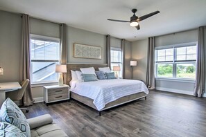 Ein Schlafzimmer mit Bett, Nachttischen, einem Schreibtisch, einem Stuhl und einem Deckenventilator.