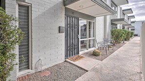 A modern two-story building with a brick facade, a balcony, and a door with a decorative metal gate.