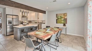 A modern kitchen with a central island, stainless steel appliances, and a dining area with a marble table and grey chairs. - Chic Scottsdale Home w/ Balcony, Walk to Old Town! (Scottsdale)