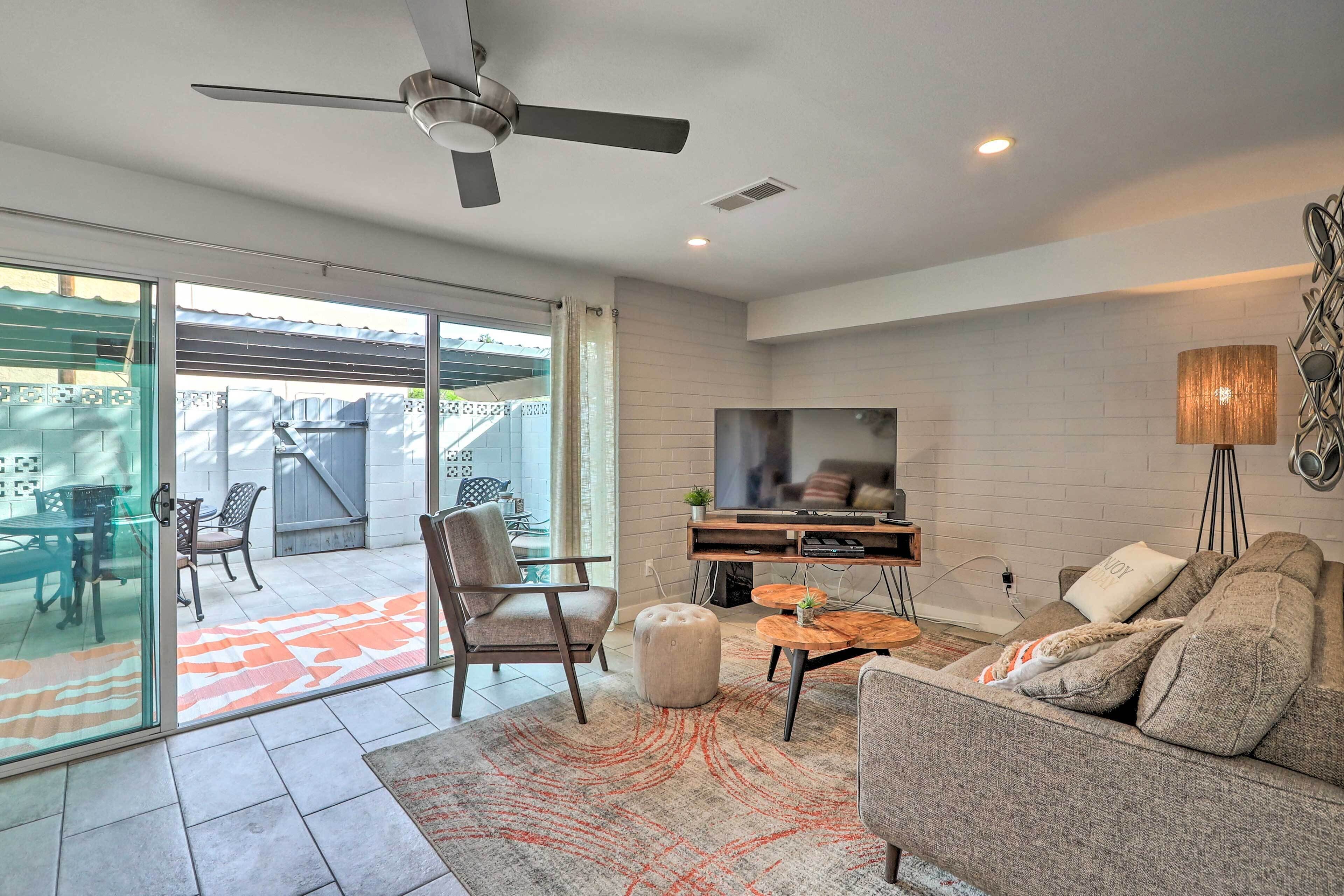 A modern living room with a flat-screen TV, a ceiling fan, and a sofa.