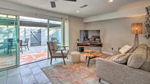 A modern living room with a flat-screen TV, a ceiling fan, and a sofa.