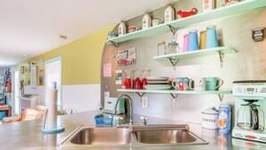 A kitchen with stainless steel appliances, a sink, and shelves with various kitchen items.