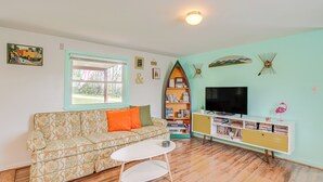 A living room with a sofa, a coffee table, a bookshelf, and a TV.