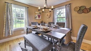 Comedor con mesa de madera dispuesta para seis personas, rodeado de sillas tapizadas.