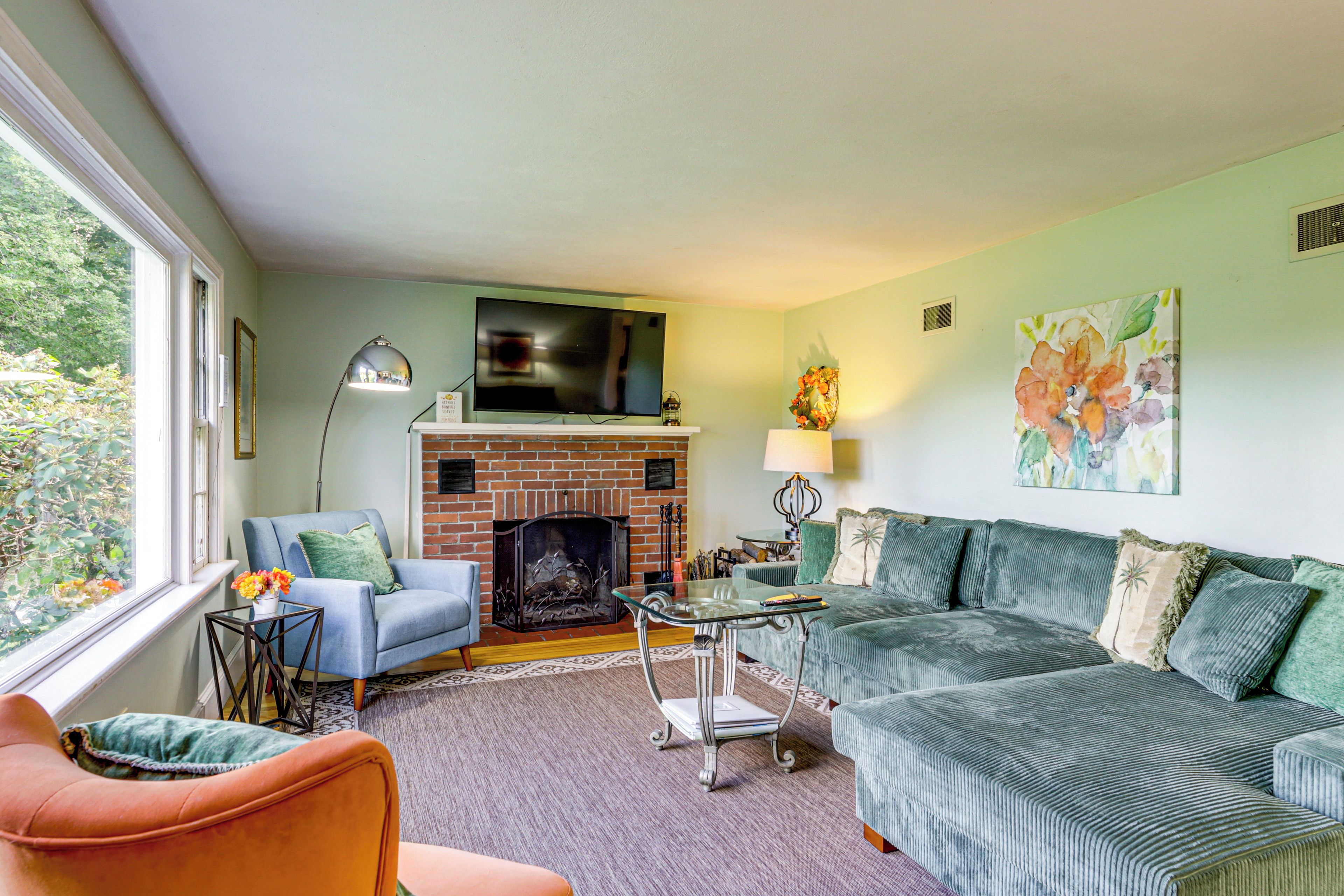 A living room with a fireplace, a television mounted above it, and two sofas.