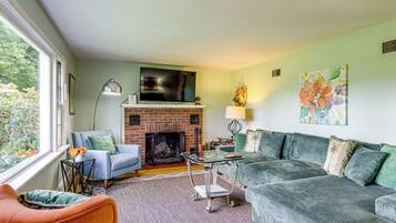 A living room with a fireplace, a television mounted above it, and two sofas.