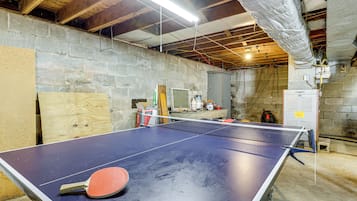 A ping pong table in a room with stone walls and exposed ceiling beams.