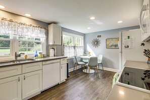 A kitchen with a dining area, wooden flooring, and a view of the outdoors. - Hampton 'quiet Corner Cottage' w/ Fireplace & Yard (Hampton)