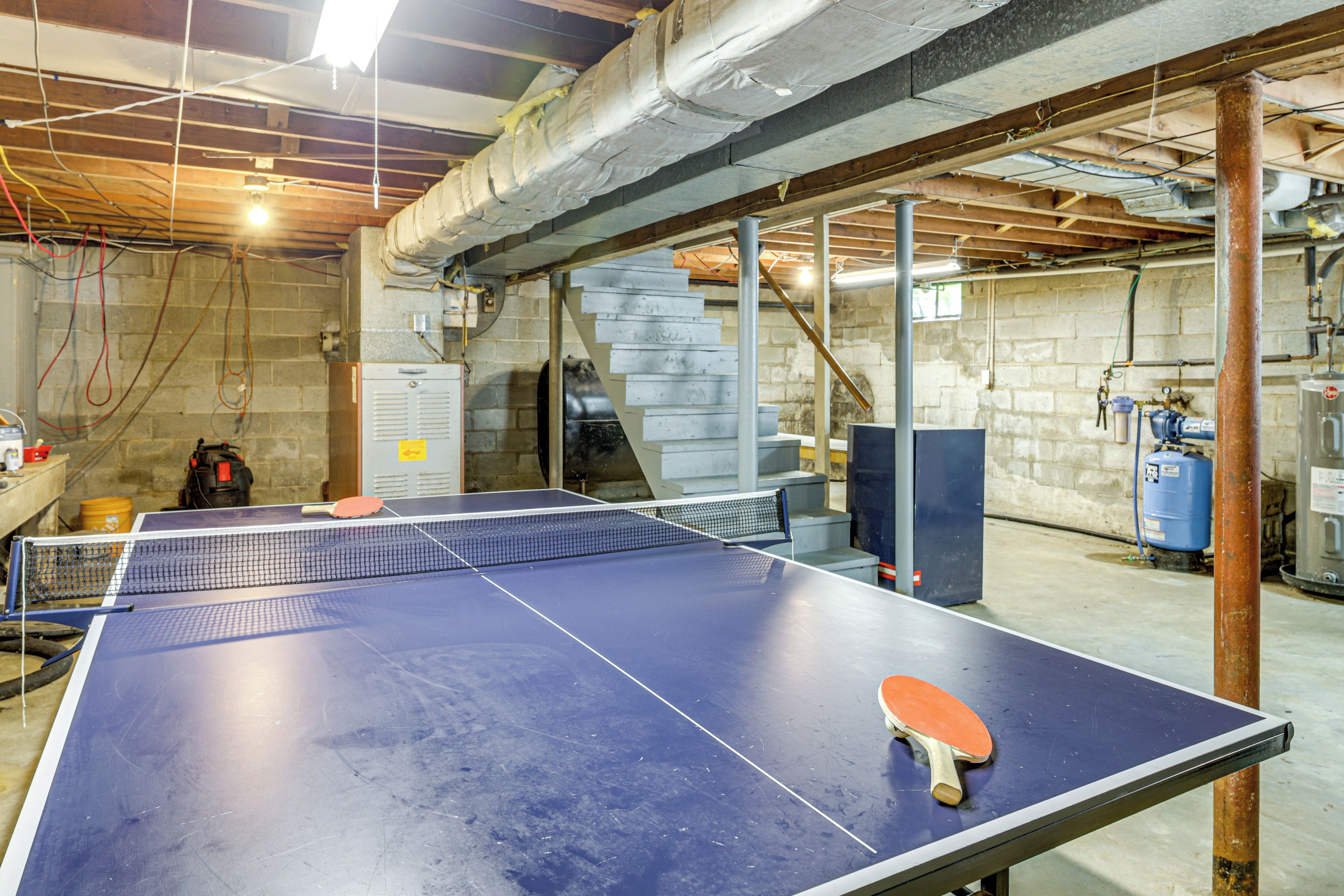 A ping pong table in a room with exposed ceiling beams and stone walls.
