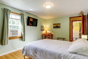 A bedroom with a bed, a desk, a chair, a television, and a window with curtains. - Hampton 'quiet Corner Cottage' w/ Fireplace & Yard (Hampton)