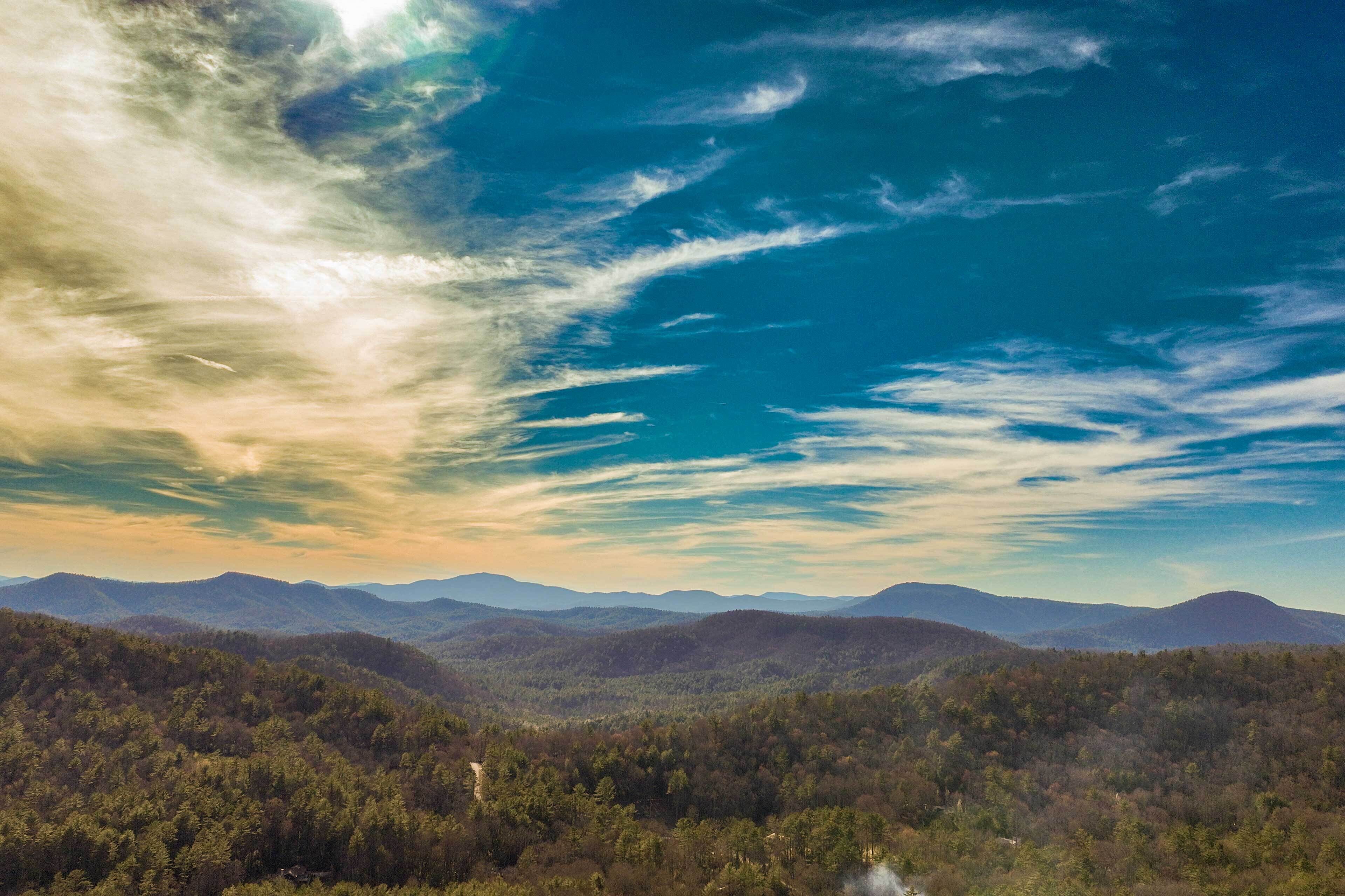 Un paisaje montañoso con un valle boscoso y cielo despejado.