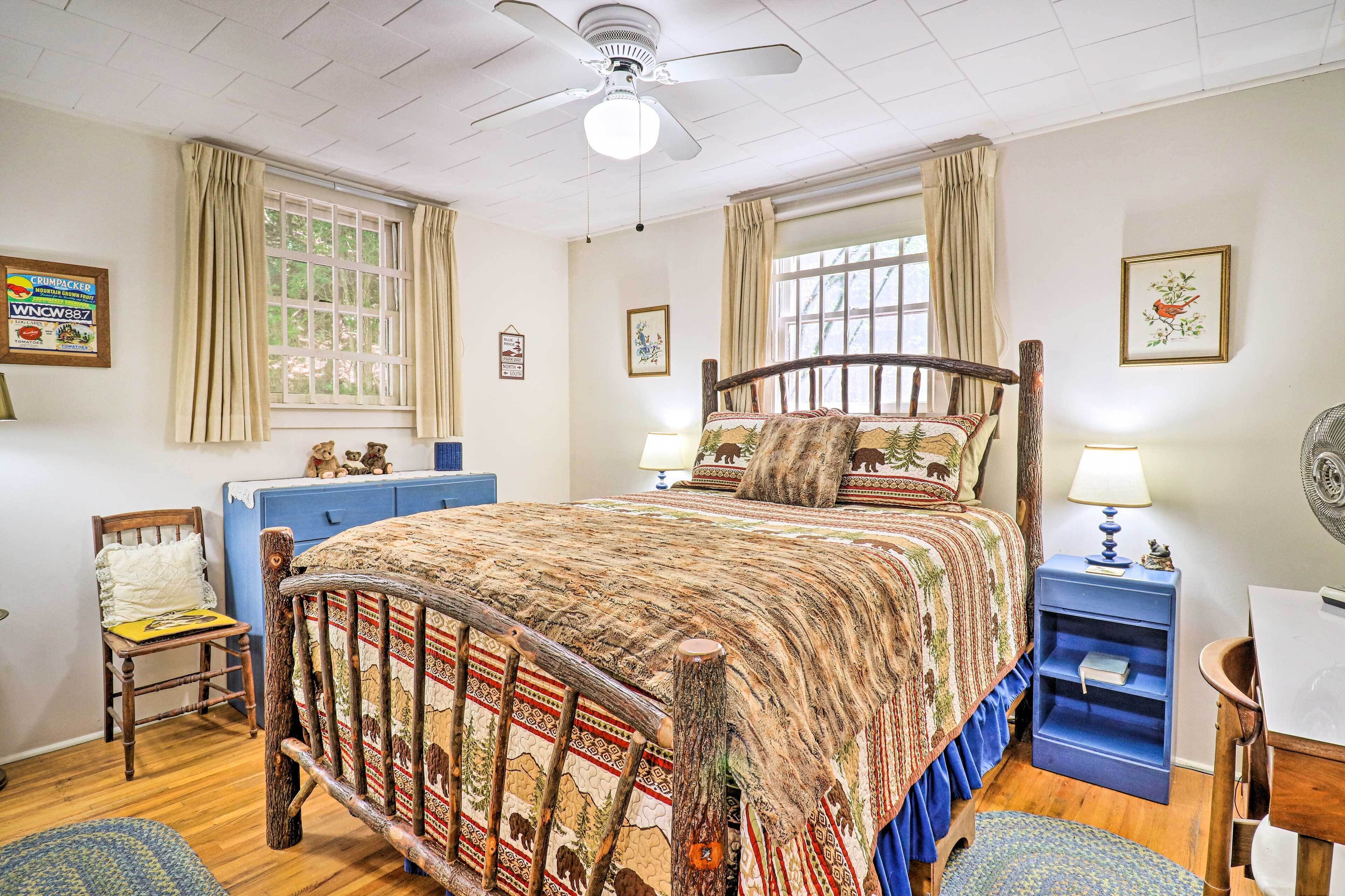 A bedroom with a wooden bed, a blue dresser, a chair, a desk, and a ceiling fan.