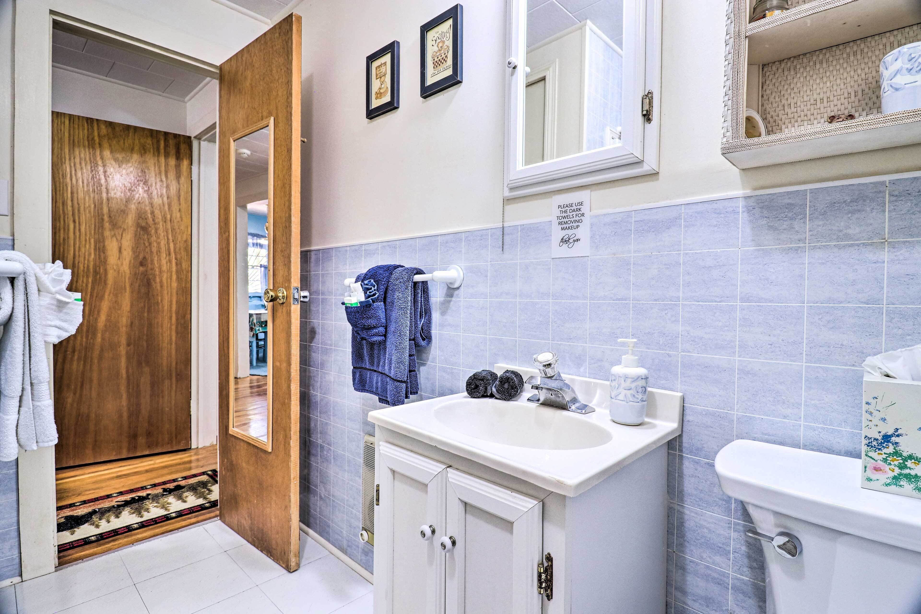 A bathroom with a wooden door, a sink with a mirror, and a toilet.