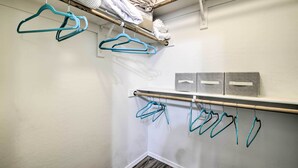 Een kast met meerdere hangstangen en planken, gevuld met opgevouwen kleding en opbergdozen.