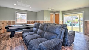 A modern living room with a pool table, leather sofa, and a view of the backyard. - Walk to Lake George: Family Escape w/ Game Room! (Lake George)