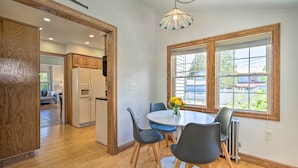 A modern kitchen with wooden cabinetry, a white refrigerator, and a dining area with a round table and chairs. - Walk to Lake George: Family Escape w/ Game Room! (Lake George)