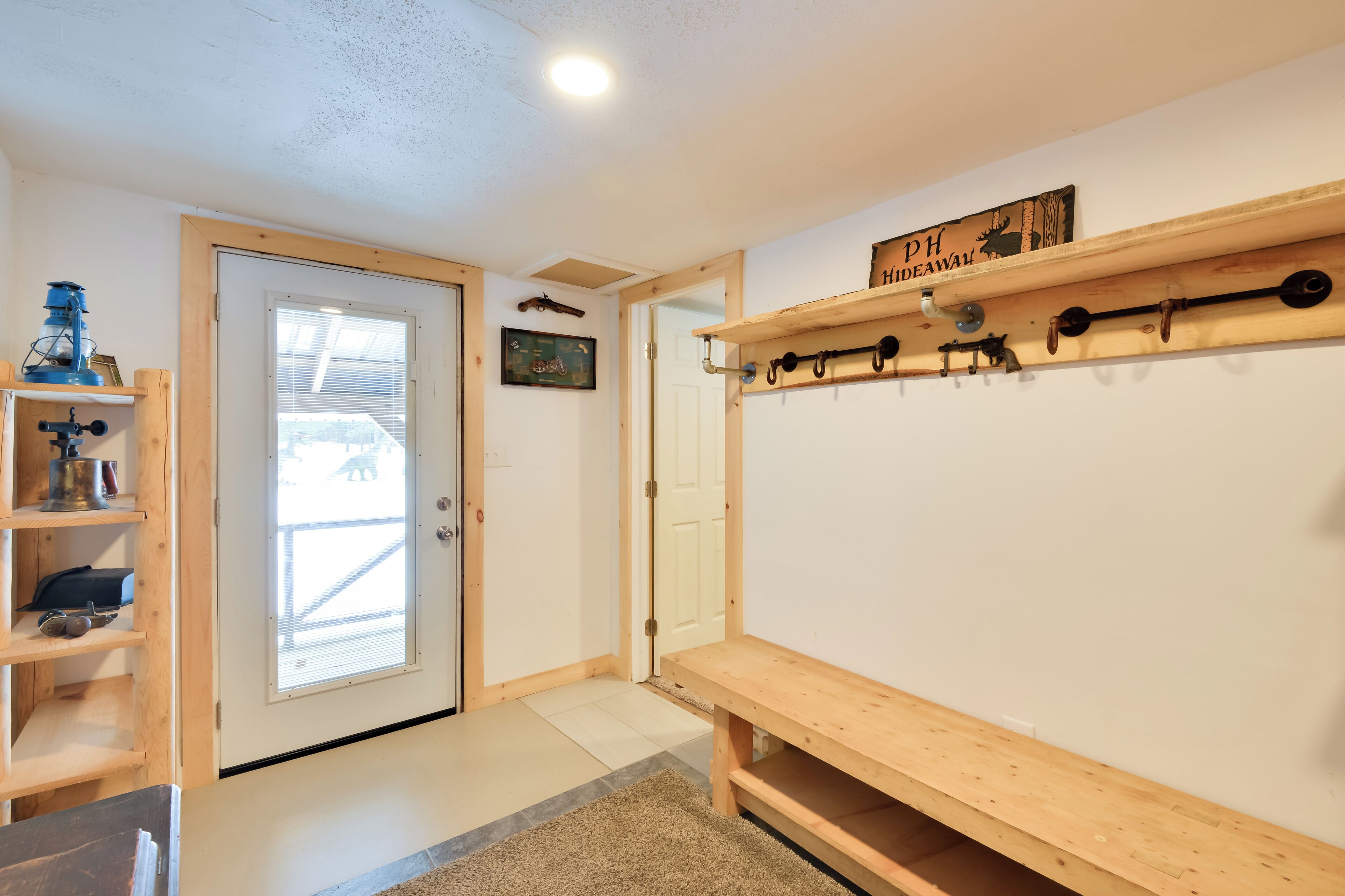 Un couloir avec un banc en bois, un porte-manteau et une porte donnant sur l’extérieur.