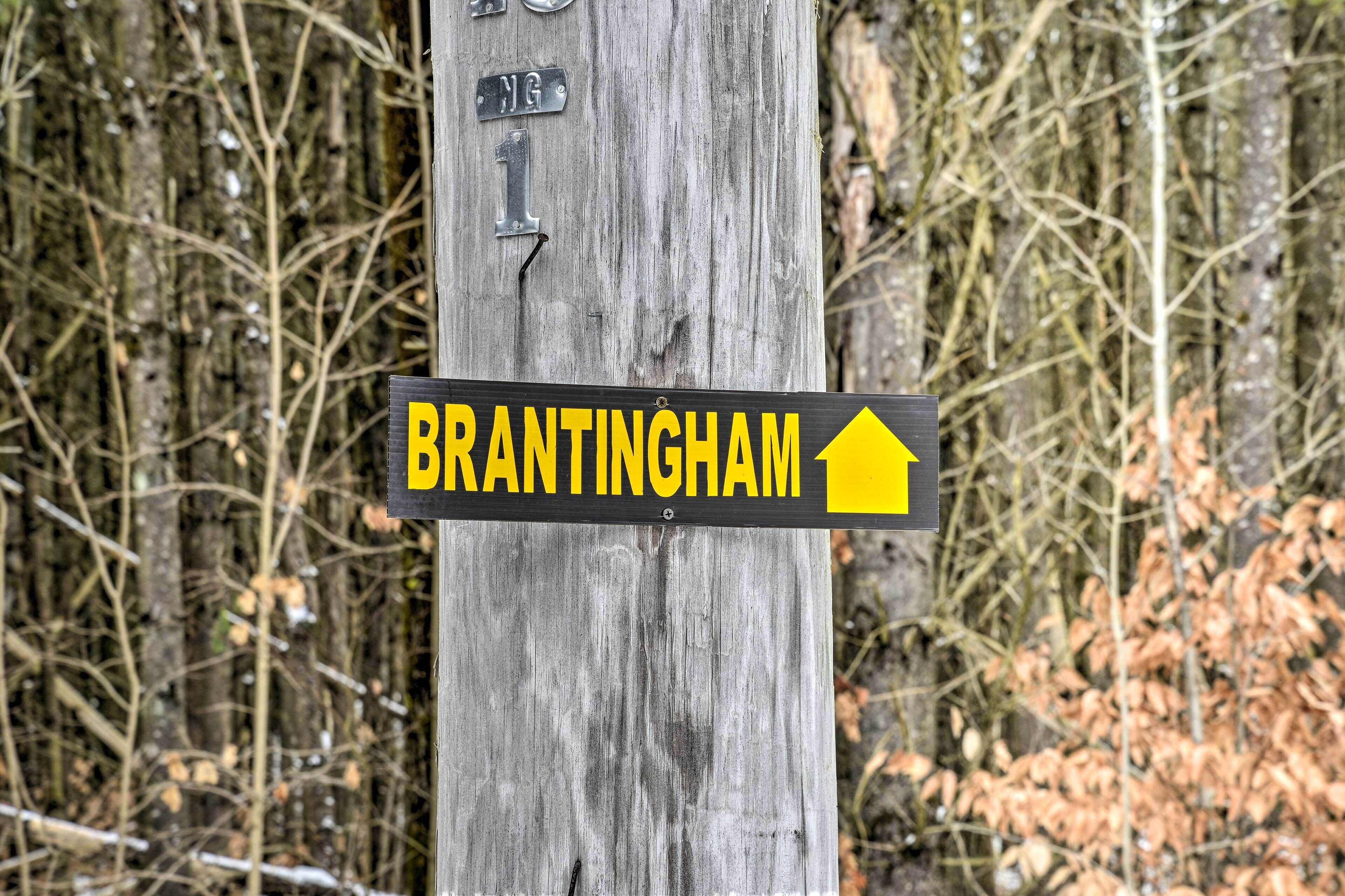 A wooden signpost with a yellow arrow pointing to the right and the word "BRANTINGHAM" in large letters.