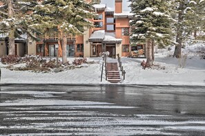 A multi-story building with a snow-covered roof and a staircase leading to the entrance.