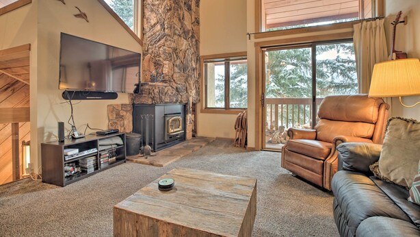 A cozy living room with a stone fireplace, a leather sofa, and a flat-screen TV. - The Mammoth Lodge by Hiking, Lakes, Skiing & More! (Mammoth Lakes)