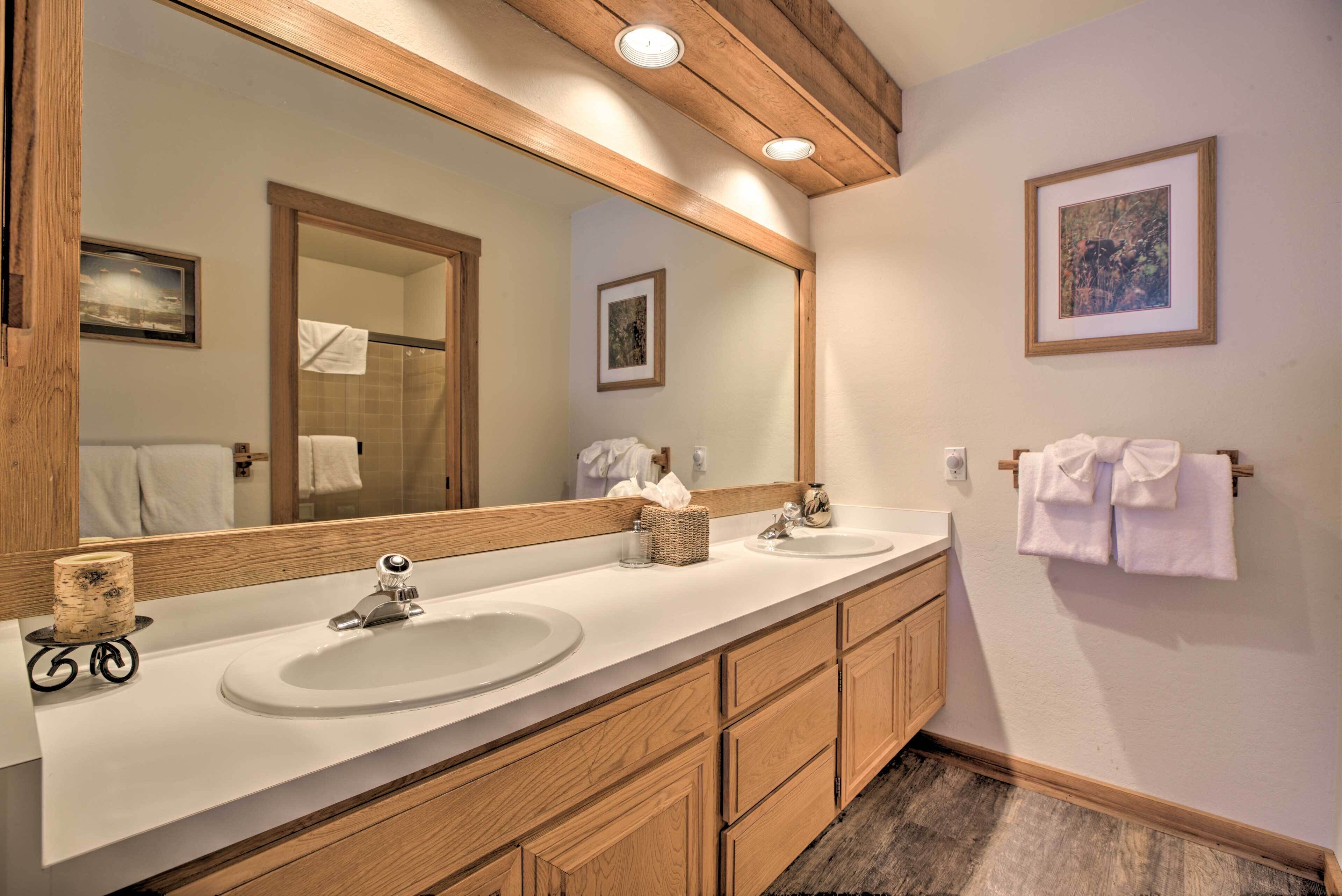A bathroom with two sinks, wooden cabinets, a large mirror, and a framed picture on the wall.