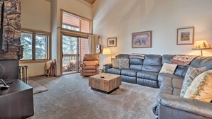 A spacious living room with a stone accent wall, a leather sofa, a wooden coffee table, and a fireplace. - The Mammoth Lodge by Hiking, Lakes, Skiing & More! (Mammoth Lakes)