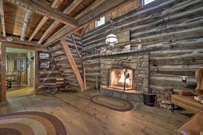 A rustic cabin interior with a stone fireplace, wooden beams, and a cozy seating area. - Historic Mountain Cabin: Grill & Hiking Trail! (Bryson City)