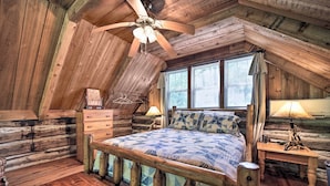 A log cabin bedroom with a wooden bed, a dresser, a nightstand, and a ceiling fan. - Historic Mountain Cabin: Grill & Hiking Trail! (Bryson City)