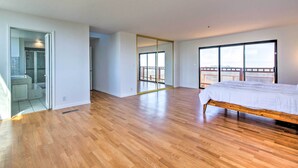 A spacious bedroom with a wooden floor, a large bed, a sliding glass door leading to a balcony, and a mirrored closet. - Spacious Royal Oaks Retreat w/ Deck & Views! (Watsonville)
