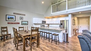 Una cocina amplia con armarios blancos, una isla central con taburetes y una zona de comedor con sillas de madera.