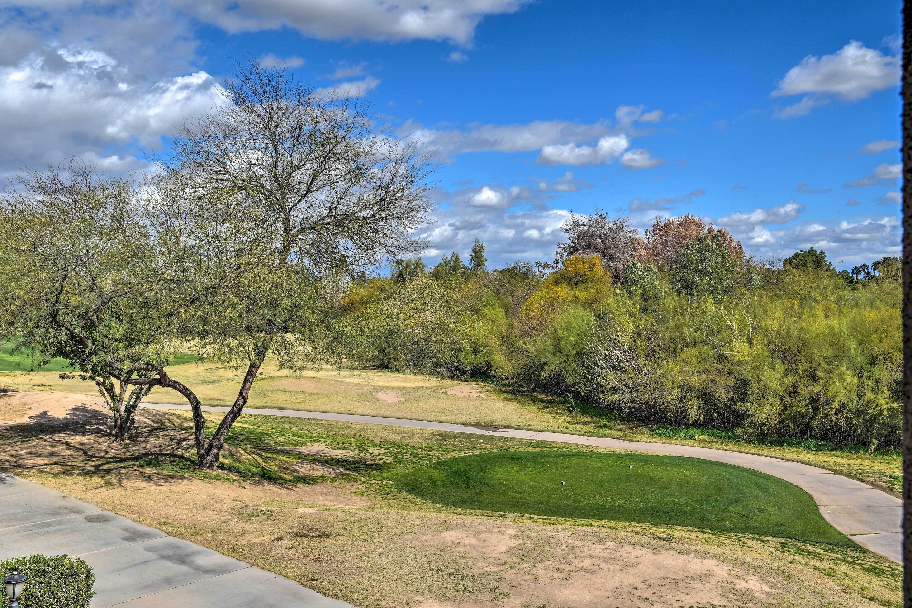 A golf course with a clear path, trees, and a well-maintained lawn.