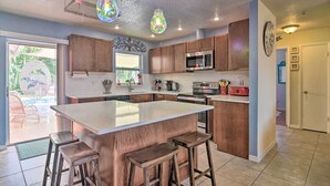 A modern kitchen with a large island, wooden cabinets, stainless steel appliances, and pendant lighting.