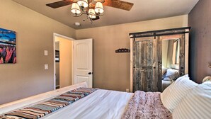 Un dormitorio con una cama grande, ventilador de techo, un cuadro y una puerta corredera.