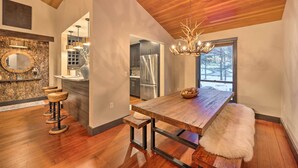 Eine moderne Küche mit Holzboden, einer Stein-Spritzschutzwand und einer großen Kochinsel mit Sitzgelegenheiten.