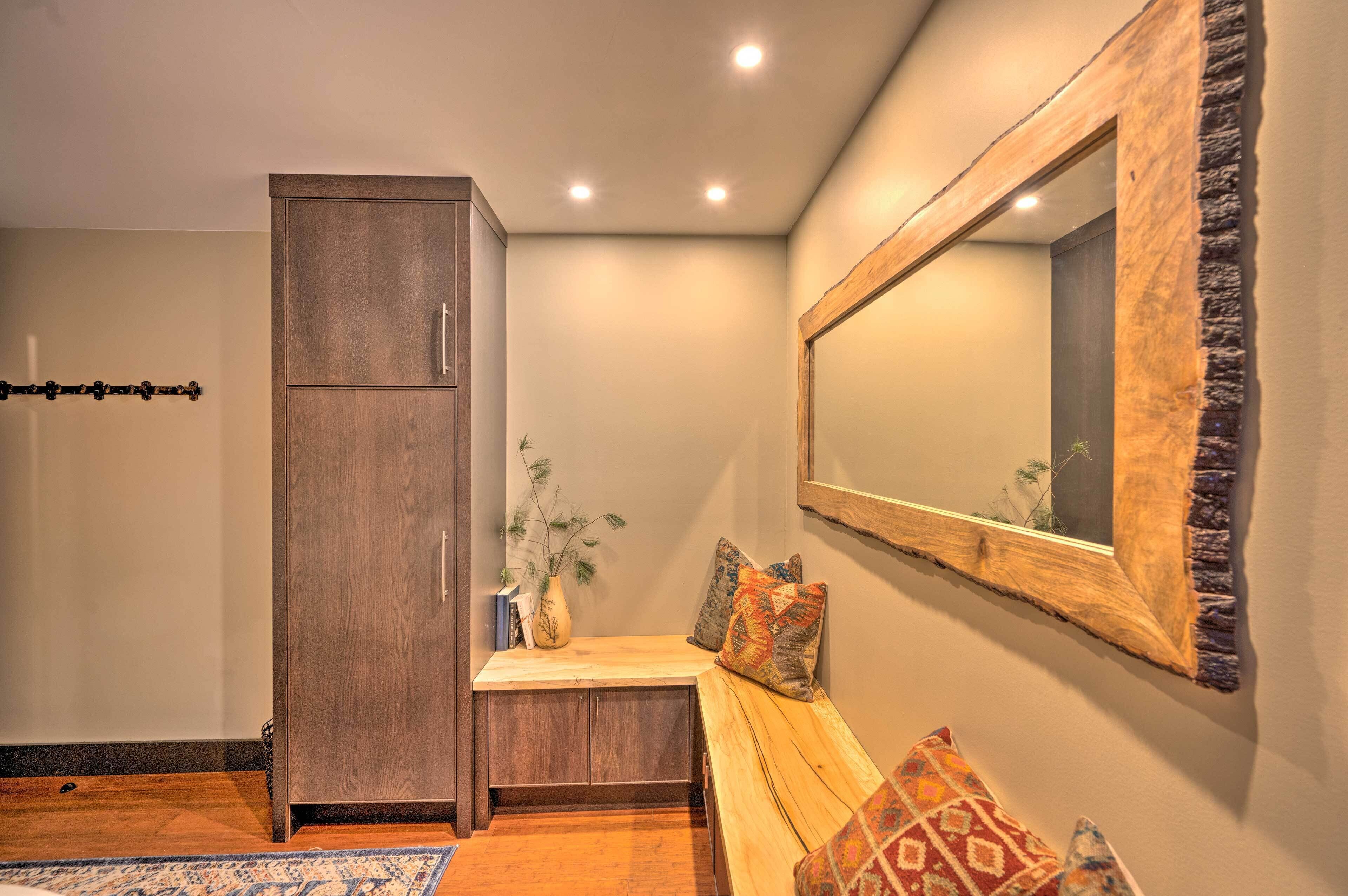 Una habitación con un banco de madera, un armario, un espejo y una planta.