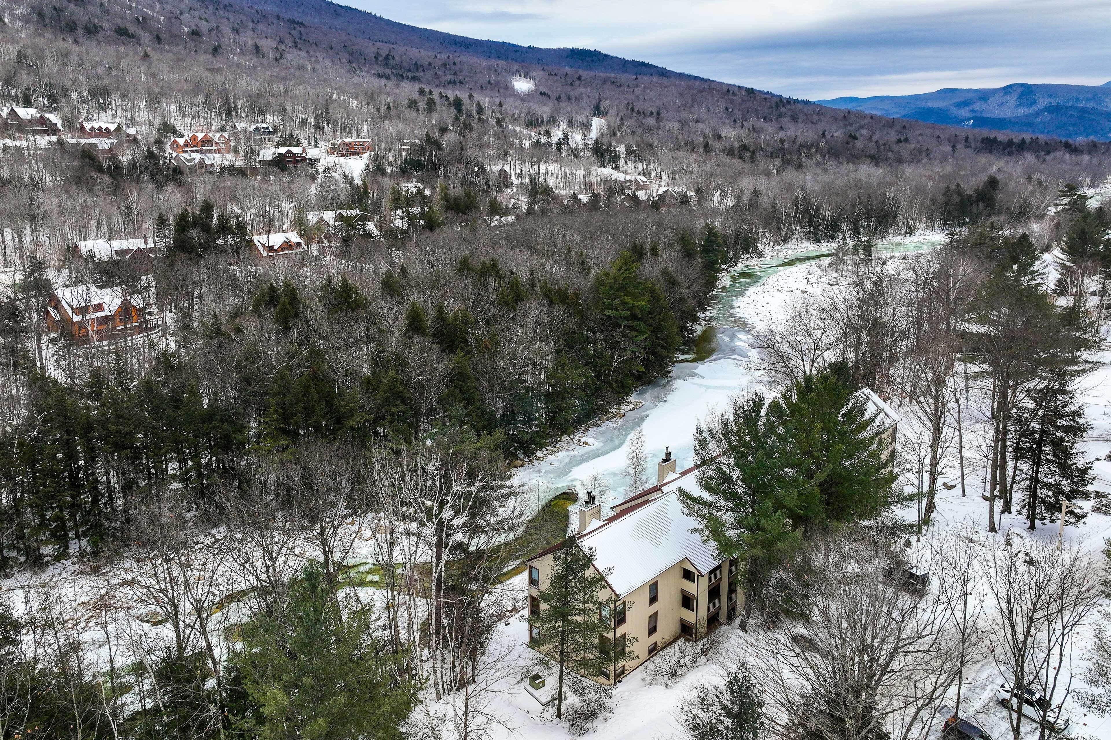Paisaje nevado con río, casas y una cabaña.