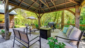A covered outdoor seating area with tables, chairs, and a sofa. - Outdoor Adventure: Tranquil Creekside Retreat (Merlin)