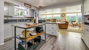 A modern kitchen with a dining area, large windows, and a view of the outdoors. - Outdoor Adventure: Tranquil Creekside Retreat (Merlin)
