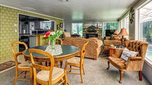 A living room with a dining table, chairs, a sofa, and a fireplace. - Outdoor Adventure: Tranquil Creekside Retreat (Merlin)