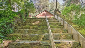 A wooden staircase with stone steps, leading to a building with a red roof. - Outdoor Adventure: Tranquil Creekside Retreat (Merlin)