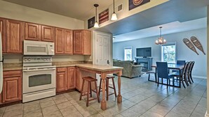 A kitchen with wooden cabinets, a white stove, and a bar stool.
