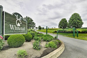 Letrero de un complejo turístico de golf con un logotipo de ciervo, rodeado de jardines cuidados y una valla verde.