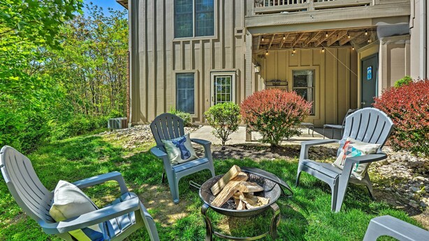 A two-story building with a balcony, outdoor seating area with chairs and a fire pit, and a well-maintained garden.