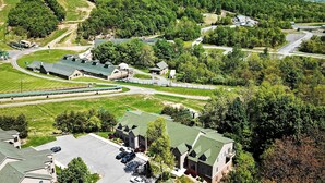An aerial view of a residential area with multiple houses, a parking lot, and a train track.