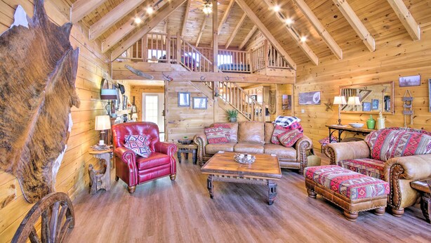 A log cabin interior with a wooden ceiling, a red leather chair, a brown leather sofa, and a wooden coffee table.