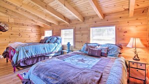 A cabin with two beds, wooden walls, and a sloped ceiling.